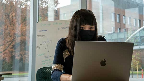 A female student wearing a mask while working at a computer