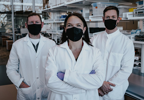 Photo of three researchers in masks and lab coats in the laboratory