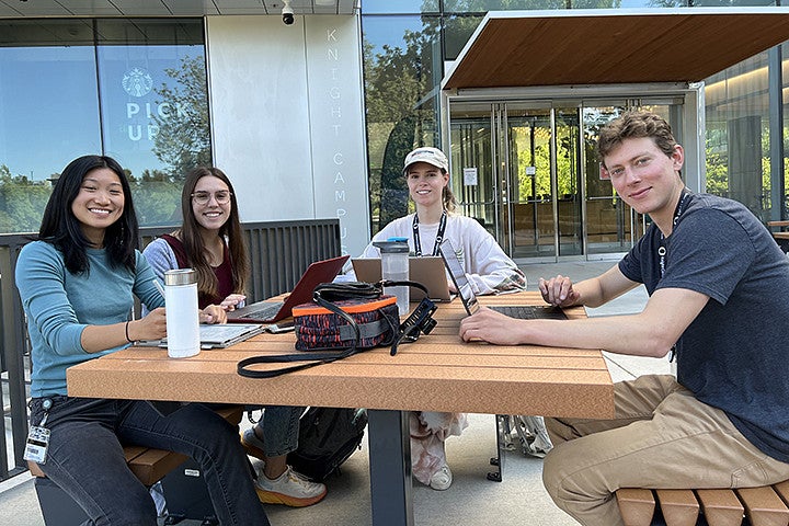 A group of college students sit at an outdoor table