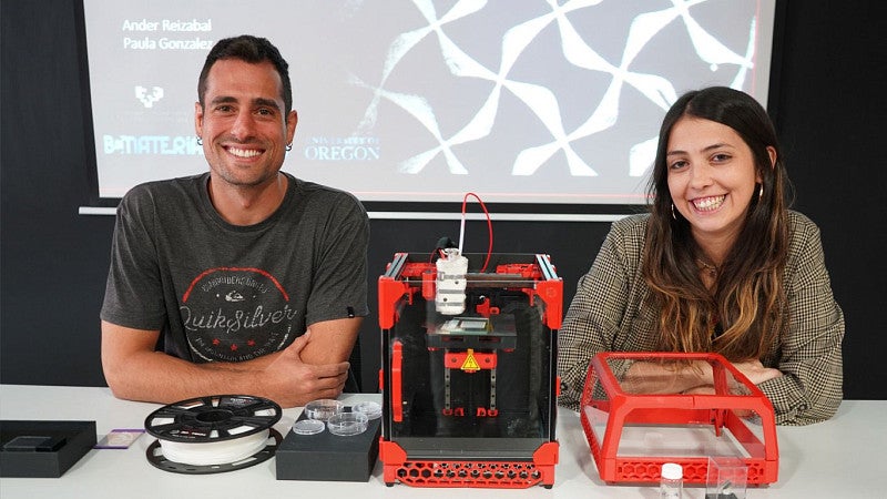 Man and woman sitting with 3d printer between them