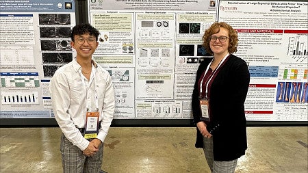 Knight Campus Undergraduate Scholar Ethan Din (left) with postdoctoral scholar Genny Romanowicz (right) stand in front of a scientific poster