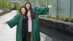 Karly Knox on left and Alexi Overland on right outside the Knight Campus building in graduation robes