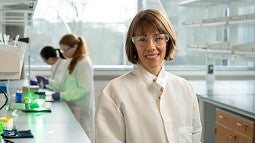 Three women in white lab coats work in a science lab