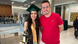 Woman with cap and gown next to man in red shirt