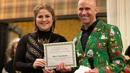 A woman and a man pose while the woman holds up a certificate