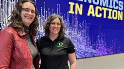 Leslie Coonrod and Stacey Wagner stand before Genomics in Action slide
