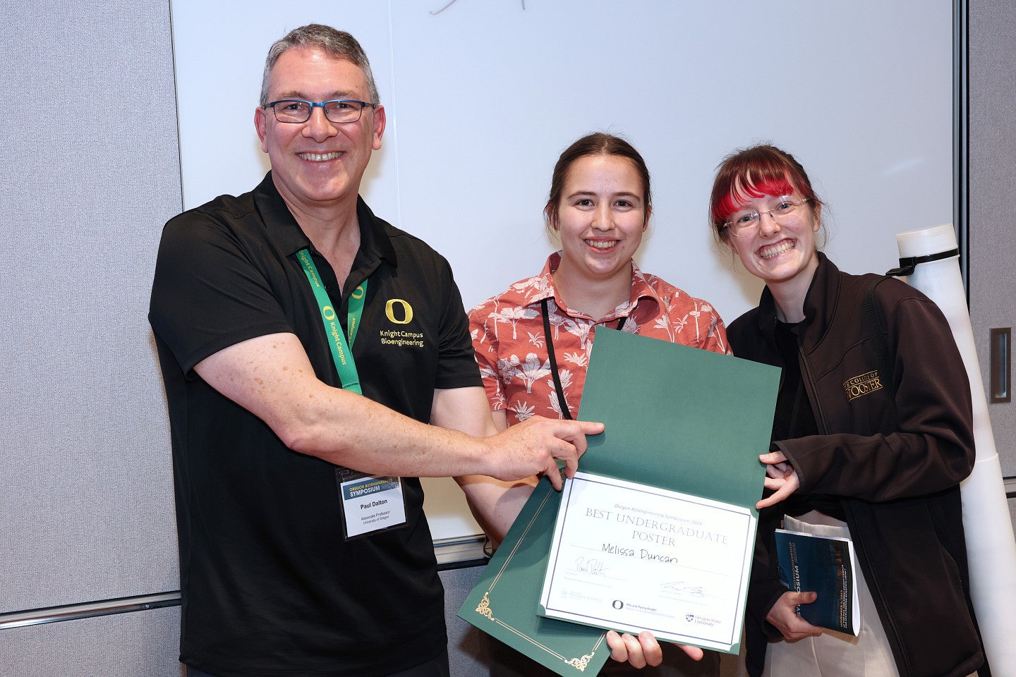 Three people holding award certificate