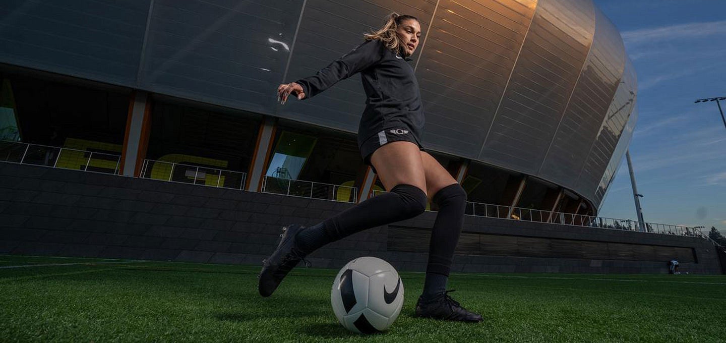 Woman in soccer uniform about to kick a soccer ball